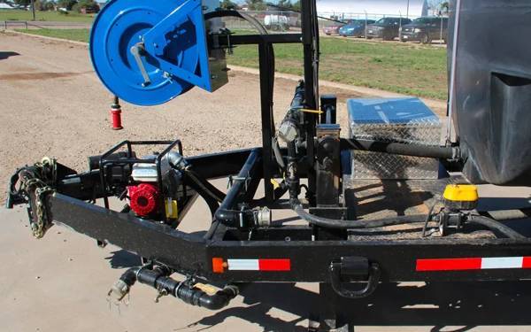 Close-up view of the water trailer showing the hose reel, pump system, and hydraulic setup.