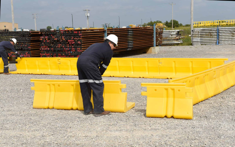Worker assembling portable containment wall for spill control