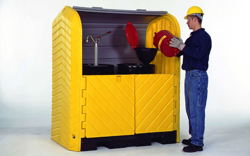 Outdoor drum storage locker with spill containment for hazardous liquids.