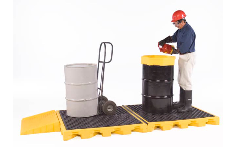 Worker using spill deck for drum containment