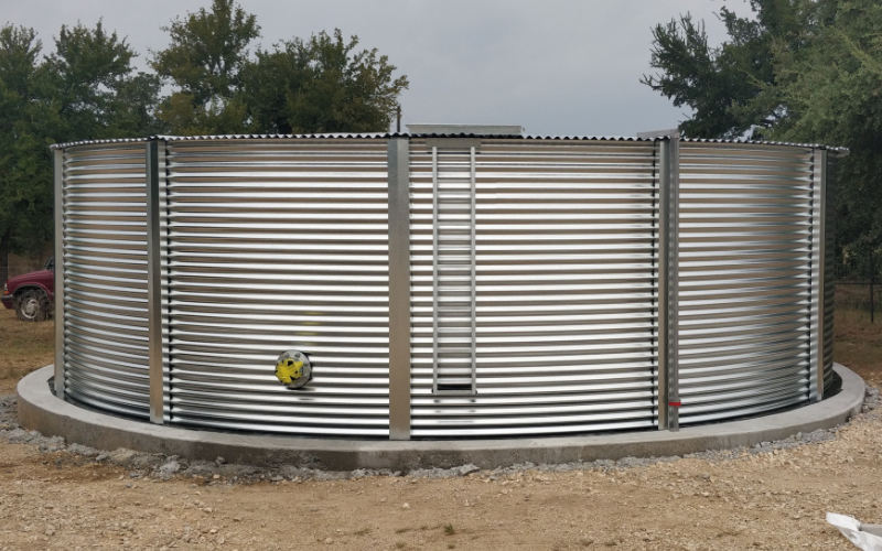 Corrugated steel tank with a conical roof, featuring industrial piping for water treatment or fire protection applications.
