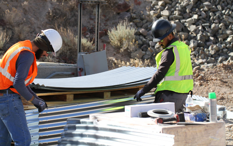 two workers in with yellow vests, checking corrugated panels to start assembly