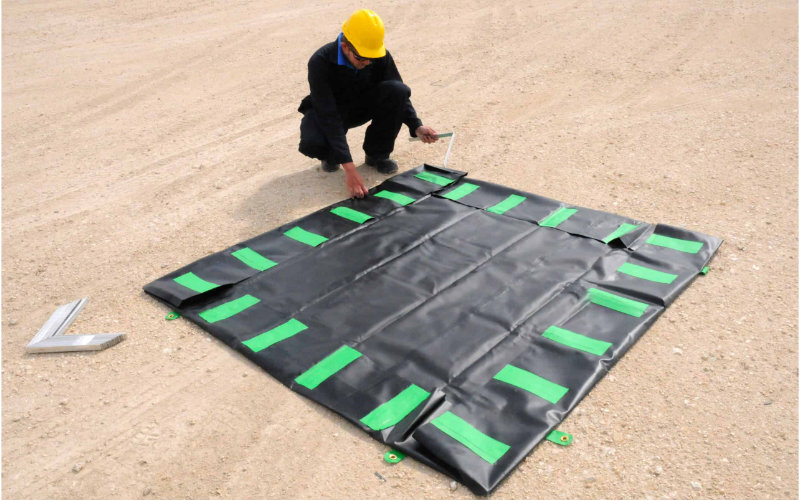 worker installing aluminum brackets of an angle berm deployed on the ground
