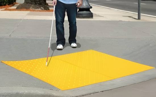 yellow ada pads on the road and a blind man about to cross