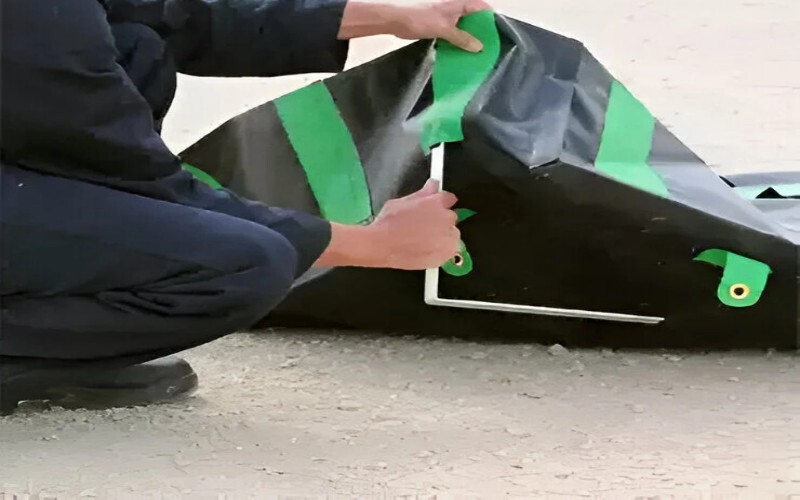 Close-up of hands securing a green containment liner with sturdy straps on a black liner base.