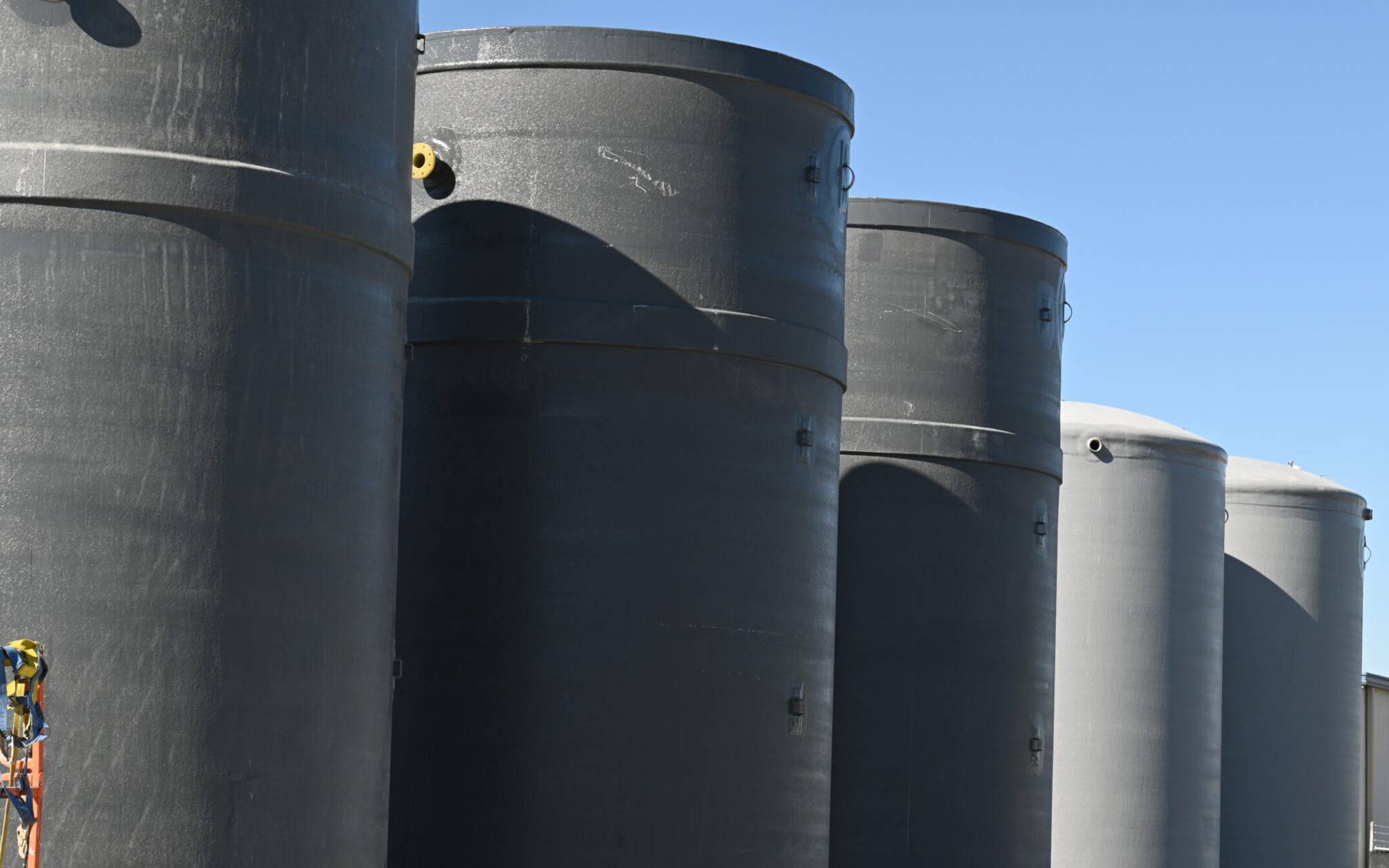 Black vertical fiberglass water storage tanks used in the oil and gas industry for liquid storage applications.
