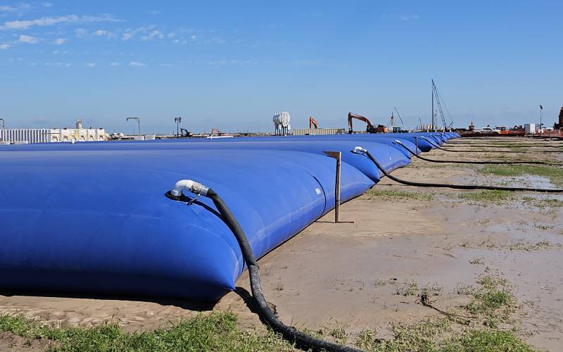 Series of blue bladder tanks deployed for industrial-scale fluid storage and pumping—ideal for frac water management or stormwater collection.