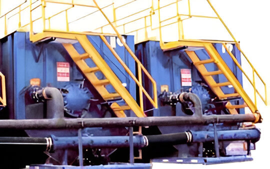 Large gray frac tank with yellow stairs, designed for industrial liquid storage and transportation, showcasing durable construction
