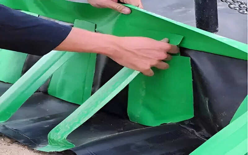 Close-up of hands adjusting and securing green straps on a black containment liner, ensuring proper installation.