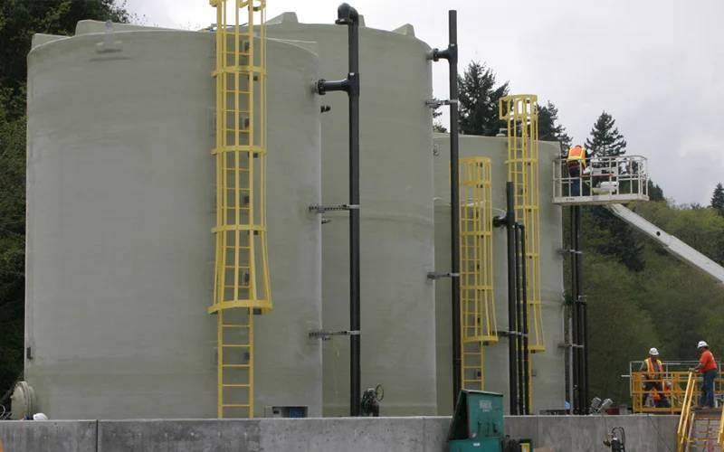fiberglass storage tanks with yellow ladders and piping systems, used for industrial liquid containment and wastewater treatment, highlighting durable and corrosion-resistant features.
