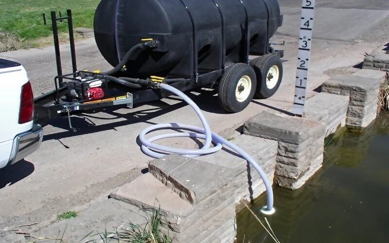 Fire fighting water trailer pulling water from a pond using a suction hose—ideal for emergency fills, brush fires, or agricultural applications.