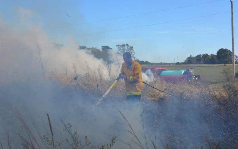 A man using a foam sprayer on grass fire