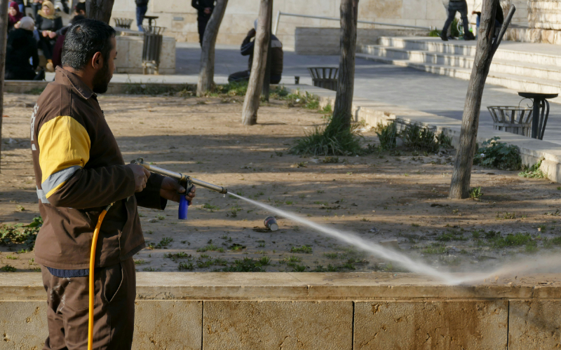 Man pressure washing outdoor pavement.