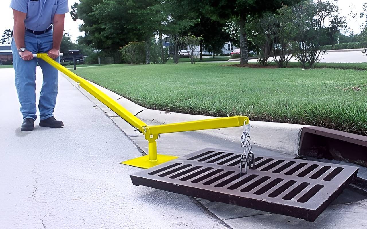 Man using grate lifter tool to remove storm drain cover