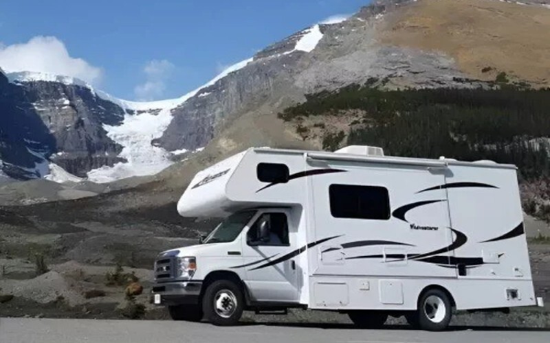 RV driving along a scenic road with mountains in the background
