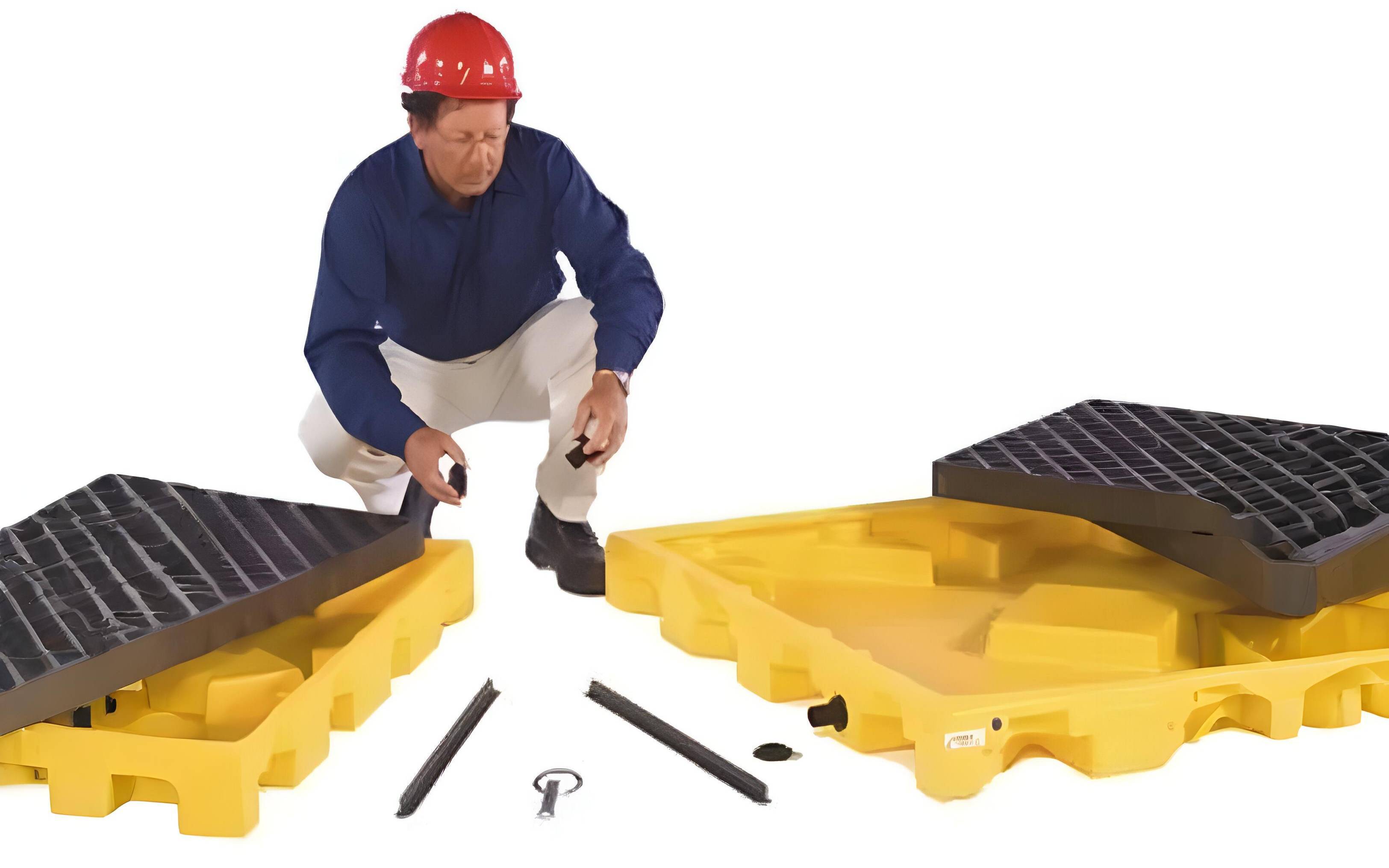 Worker assembling a yellow spill containment deck with black grates using spill deck accessory kit.