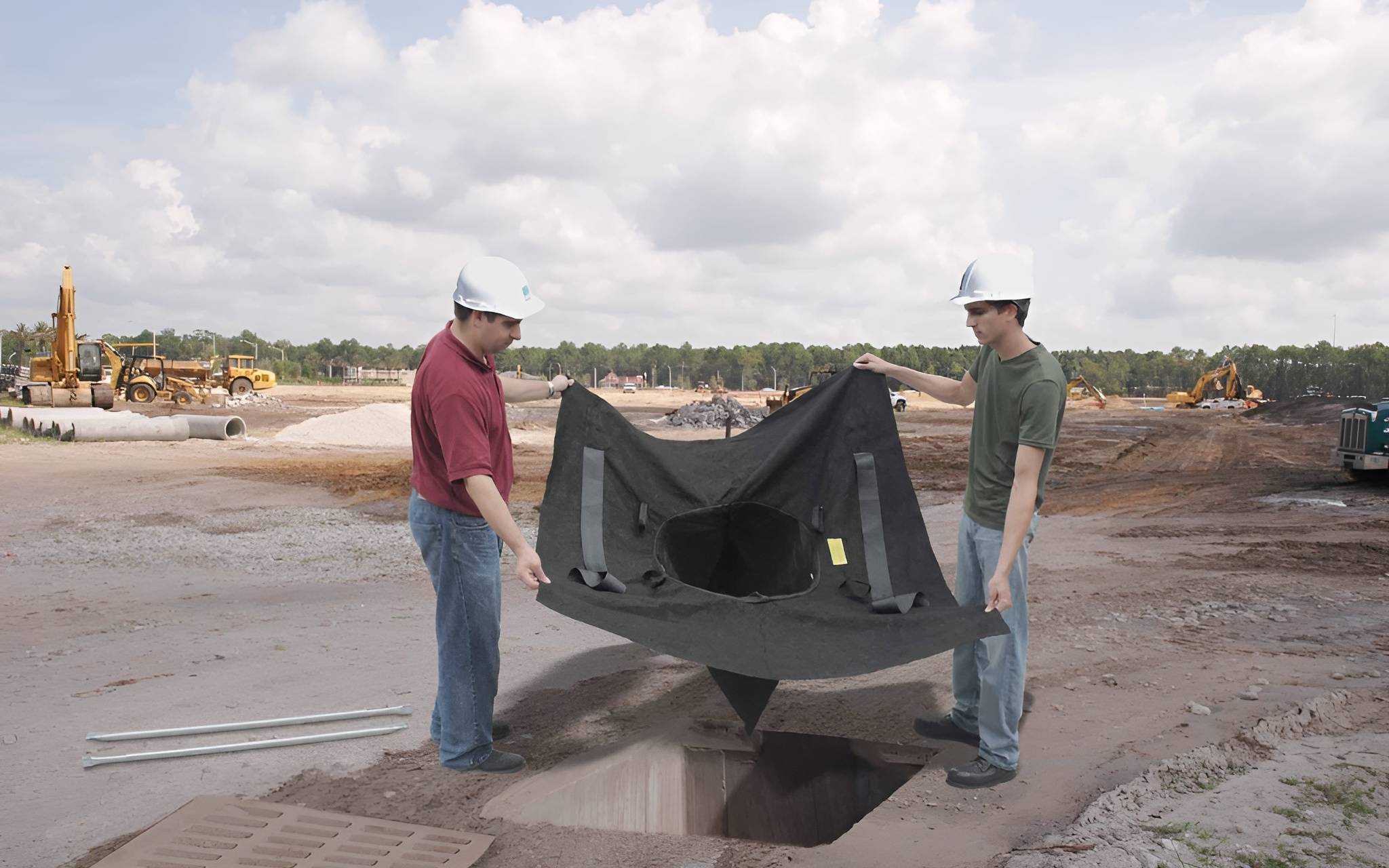 Two men holding high-capacity drain guard at construction site