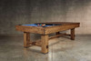 ¾ view of the Doc & Holliday Churchill Rustic Pool & Billiard Table in Distressed Burl Pine with the 3-piece leaf dining top half on, one leaf turned to reveal Championship blue felt. Rustic distressed finish and custom buffalo nickel billiard sights highlight its USA-built craftsmanship.