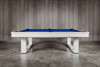 Full side profile view of the Doc & Holliday Santorini Slate Pool Table, shown in a custom white finish with Euro Blue Championship felt. Handcrafted in the USA from solid hardwood, photographed against an RH-style concrete backdrop. Modern luxury dining pool table by Doc & Holliday Billiards.