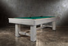 ¾ lifestyle view of the Doc & Holliday Churchill Pool Table in Smoked Maple distressed grey finish with Championship felt, staged against a moody concrete wall backdrop with soft ambient light.