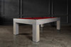 The Natural Slate Pool Table by Doc & Holliday in Grey Wash — three-quarter front view in a designer game room with Restoration Hardware-inspired décor, shown with bold red Championship felt.