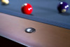 Close-up detail of The Hank Slate Pool Table by Doc & Holliday Billiards in Americana Chocolate, showing the hammered metal billiard sight inset on the maple hardwood rail above the Championship Titanium felt.