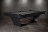 Three-quarter lifestyle view of the Doc & Holliday TRON Slate Pool Table in matte black finish | Ultra-modern industrial steel frame with solid maple hardwood accents and black felt playfield | Photographed in a luxury interior setting, highlighting the sculptural silhouette and dramatic design | USA-made contemporary billiards furniture by Doc & Holliday Billiards