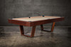 Doc & Holliday Zoey slate pool table, made in the USA, photographed at a three-quarter angle; tapered U-legs in warm maple, 1″ three-piece K-pattern slate, leather drop pockets, and mother-of-pearl sights styled as a modern lounge centerpiece.