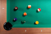 Top-down overhead view of Paula Parsons Pool Table corner pocket, Grey Walnut frame with abalone diamond sights, and multiple billiard balls on green felt