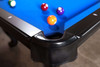 Close detail of the hand-stitched leather drop pocket set into the black hardwood rail. The mother-of-pearl diamond sight and maple rail edge show the craftsmanship and accuracy built into this American-made slate pool table.