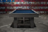 Side profile of the Doc & Holliday Hank Pool Table in the Gray Marble finish, photographed on a raw concrete floor with a distressed corrugated-steel American flag backdrop, highlighting the table’s solid oak build, slate-bed precision, and modern American craftsmanship.