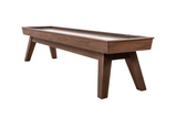 Three-quarter angle view of the George Shuffleboard Table in Grey Walnut finish by Doc & Holliday, photographed on a white background, showcasing mid-century flared legs, recessed scoring, and maple butcher block playfield.