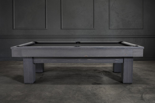 Side profile of the Doc & Holliday Dallas Slate Pool Table in Smoke Maple finish, captured in a professional lifestyle photo shoot with a design-forward backdrop. Emphasizes the bold Parsons-style silhouette, distressed grey wash pine grain, apron joinery, genuine leather drop pockets, and smooth Championship felt surface.
