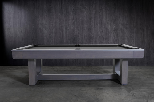 Side profile of the Doc & Holliday Everly Slate Pool Table in Smoke Maple finish, photographed in a styled studio backdrop inspired by Restoration Hardware interiors. Emphasizes the flowing leg silhouette, oak craftsmanship, soft maple grain detail, and genuine leather drop pockets.