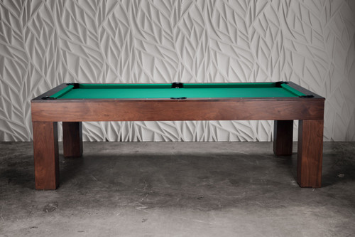 Luxury pool table in natural walnut finish by Doc & Holliday, captured at a three-quarter angle against a modern industrial-inspired studio background for a high-end lifestyle presentation.