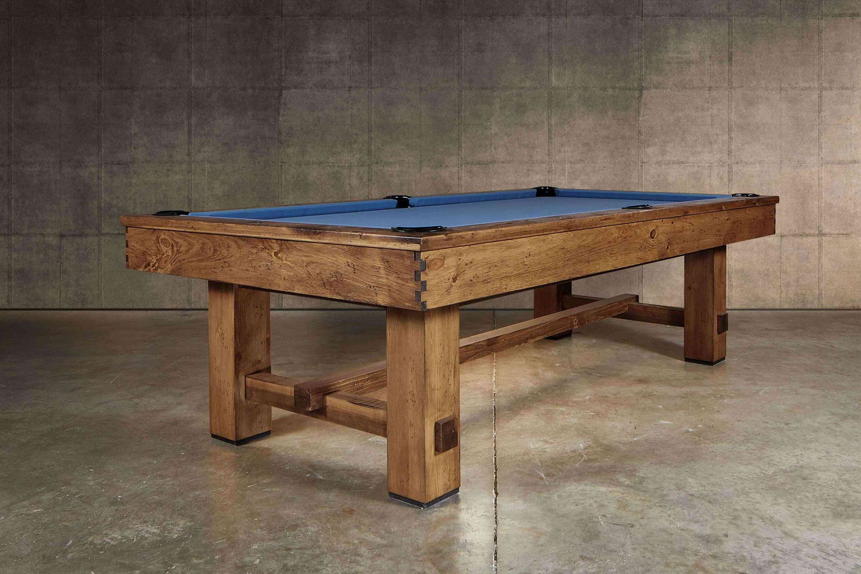 Hero ¾ view of the Doc & Holliday Churchill Rustic Pool & Billiard Table in Distressed Burl Pine with Championship blue felt, shown as the lead image from the photo shoot. Distressed pine frame, leather drop pockets, and custom buffalo nickel billiard sights highlight its USA-built craftsmanship.
