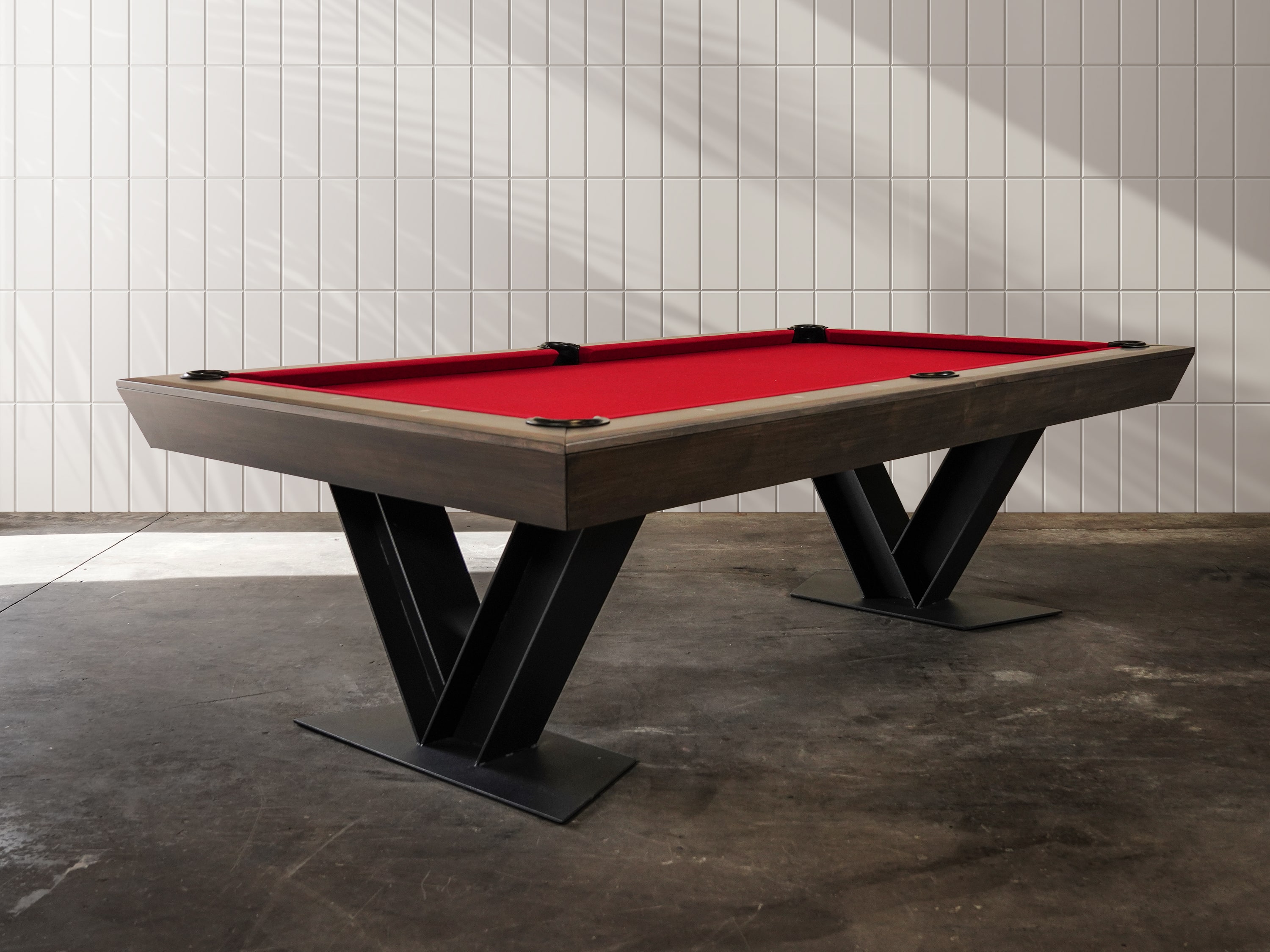 Doc & Holliday Savant slate pool table with tapered maple rails in Brown Sugar finish and bold matte black steel V-shaped base, modern luxury design perfect for loft or high-end entertainment space.