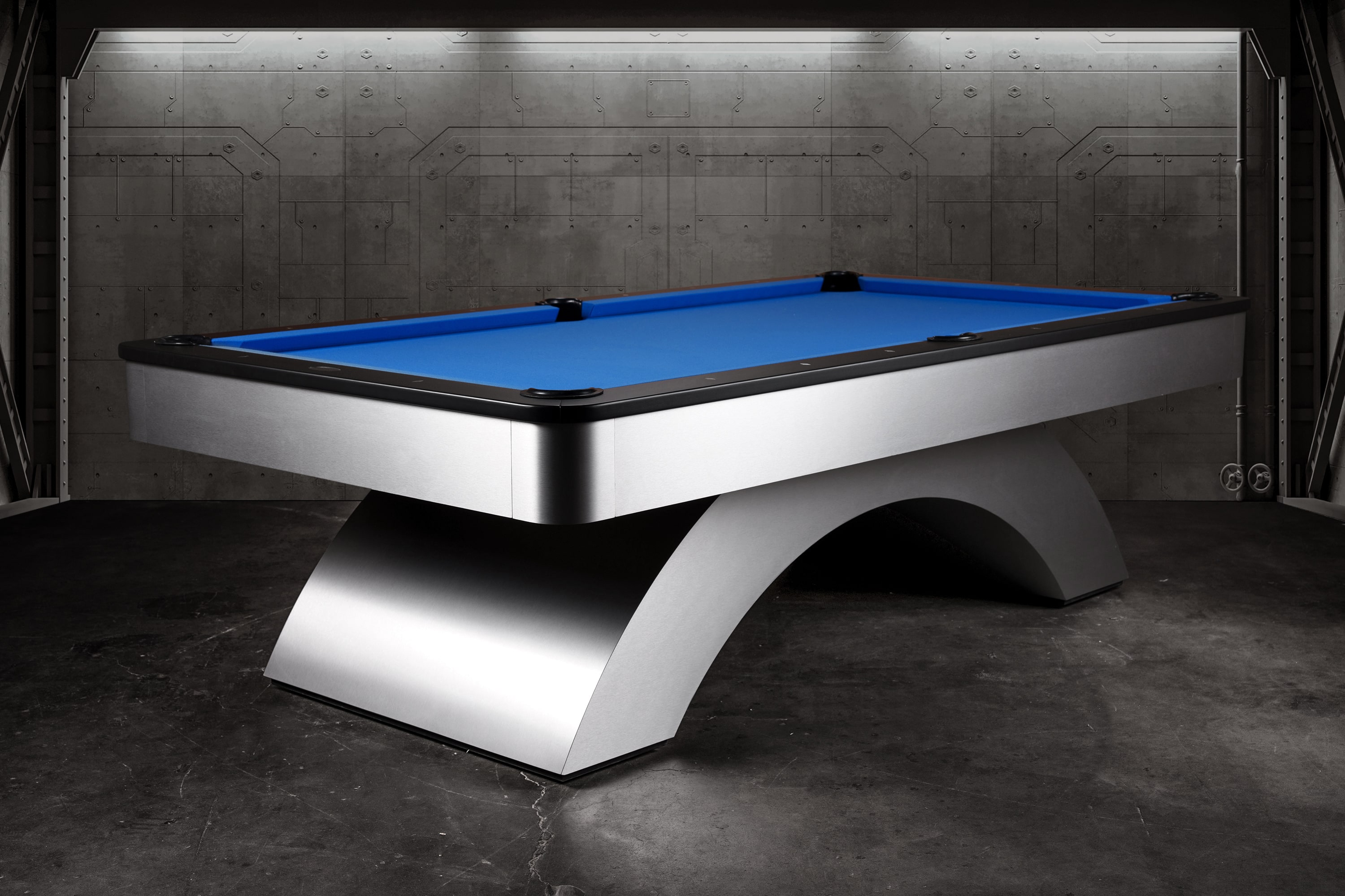Three-quarter view of the Doc & Holliday Poshy Rainbow Slate Pool Table, showing its full metallic arc base with rainbow gradient, matte black upper rails, and Euro Blue Championship felt, staged on a concrete floor with a clean backdrop wall.