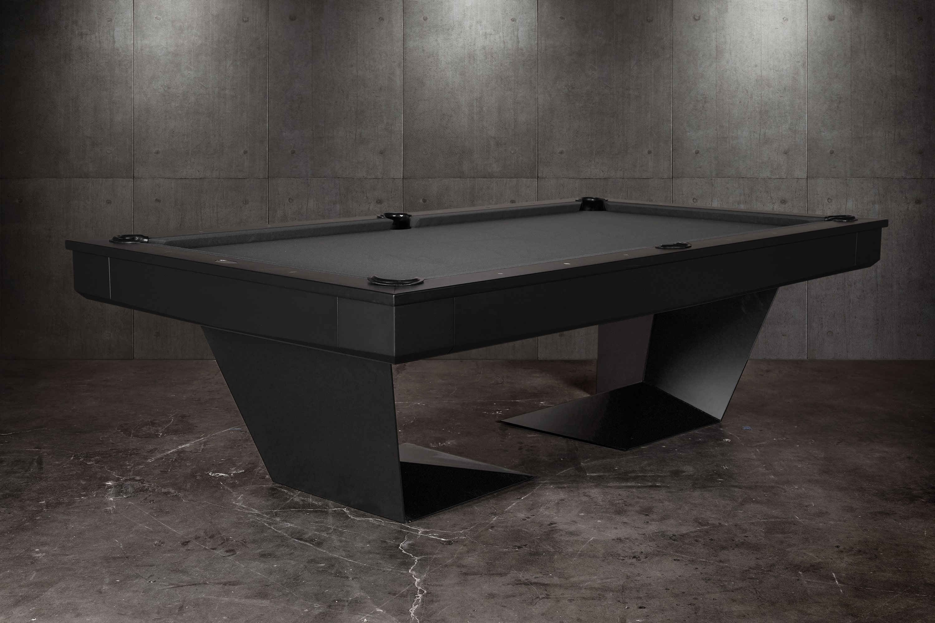 Three-quarter lifestyle view of the Doc & Holliday TRON Slate Pool Table in matte black finish | Ultra-modern industrial steel frame with solid maple hardwood accents and black felt playfield | Photographed in a luxury interior setting, highlighting the sculptural silhouette and dramatic design | USA-made contemporary billiards furniture by Doc & Holliday Billiards