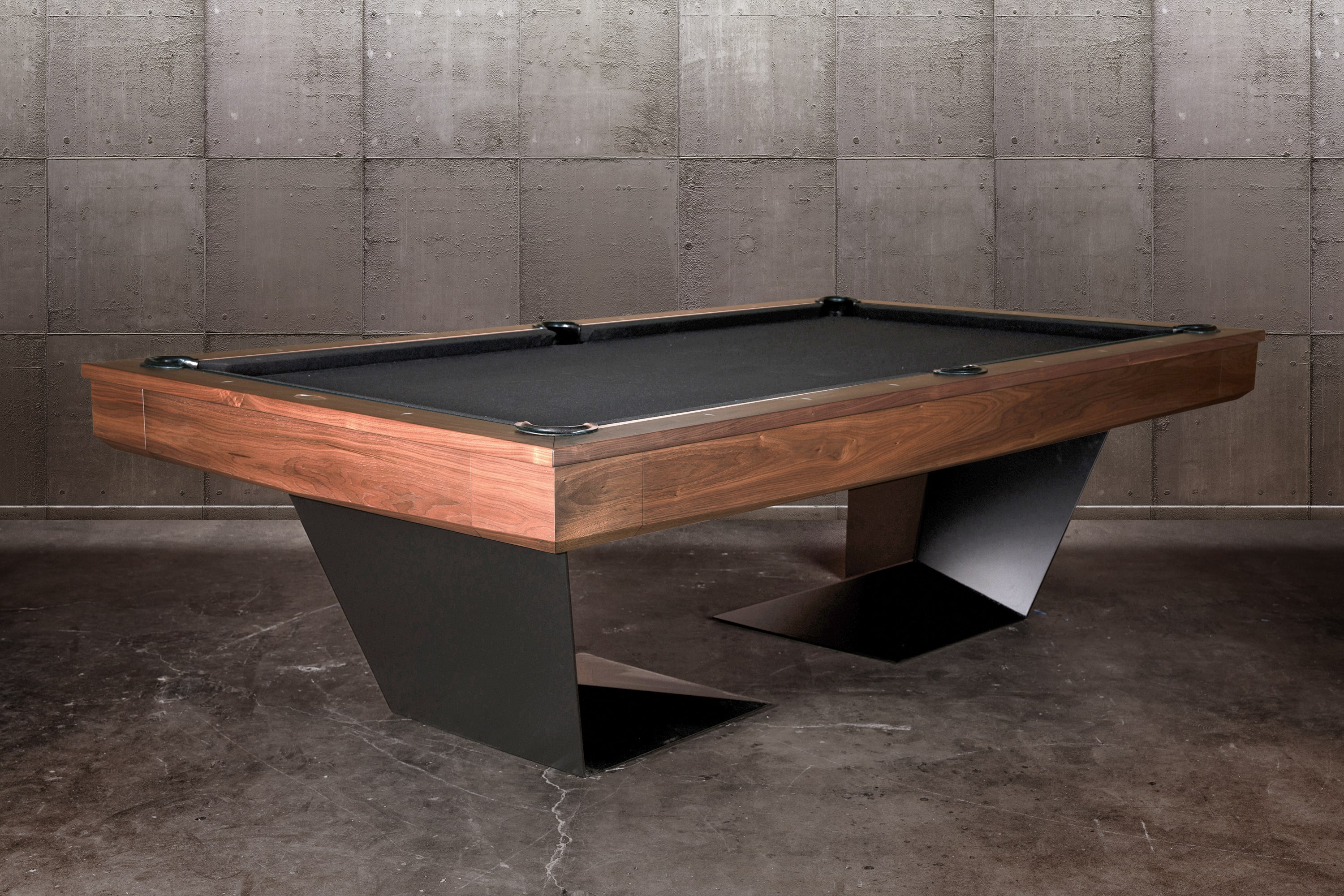 Three-quarter lifestyle view of the Doc & Holliday TRON Steel Pool Table with premium solid walnut hardwood top | Industrial steel frame paired with rich walnut wood grain, matte black base, and slate playfield | Photographed in a luxury designer interior to highlight the striking contrast of warm walnut and modern steel | USA-made contemporary billiards by Doc & Holliday Billiards