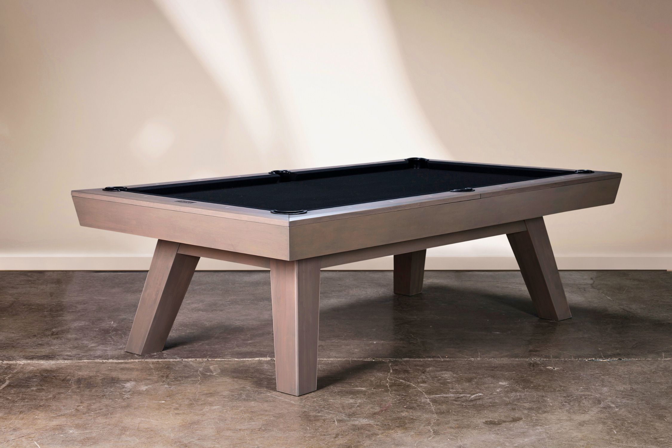 The George Slate Pool Table in Glazed Pearl staged in a bright lifestyle setting. The finish and flared legs create a sophisticated centerpiece for luxury homes or hospitality spaces.
