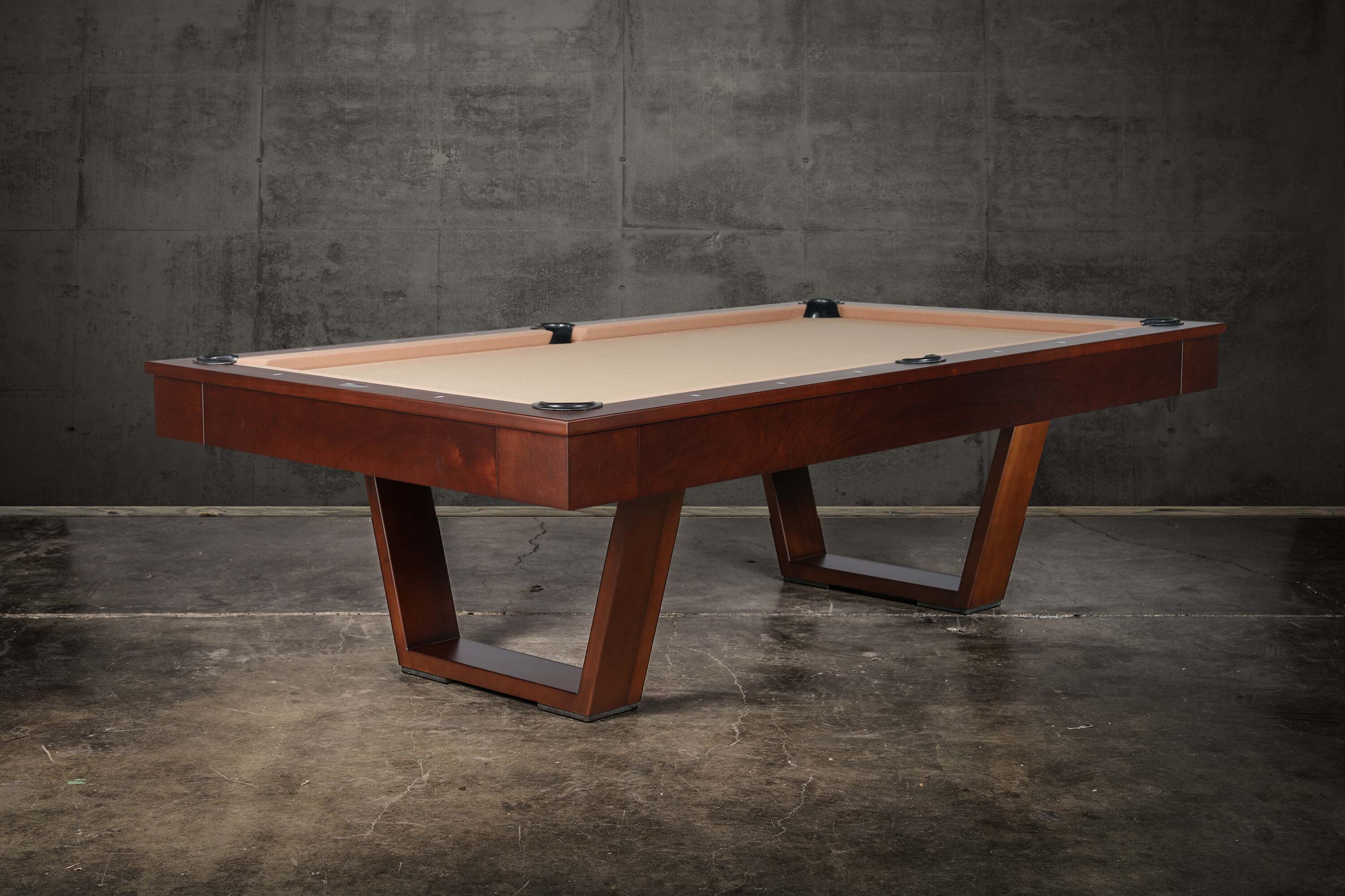 Doc & Holliday Zoey slate pool table, made in the USA, photographed at a three-quarter angle; tapered U-legs in warm maple, 1″ three-piece K-pattern slate, leather drop pockets, and mother-of-pearl sights styled as a modern lounge centerpiece.
