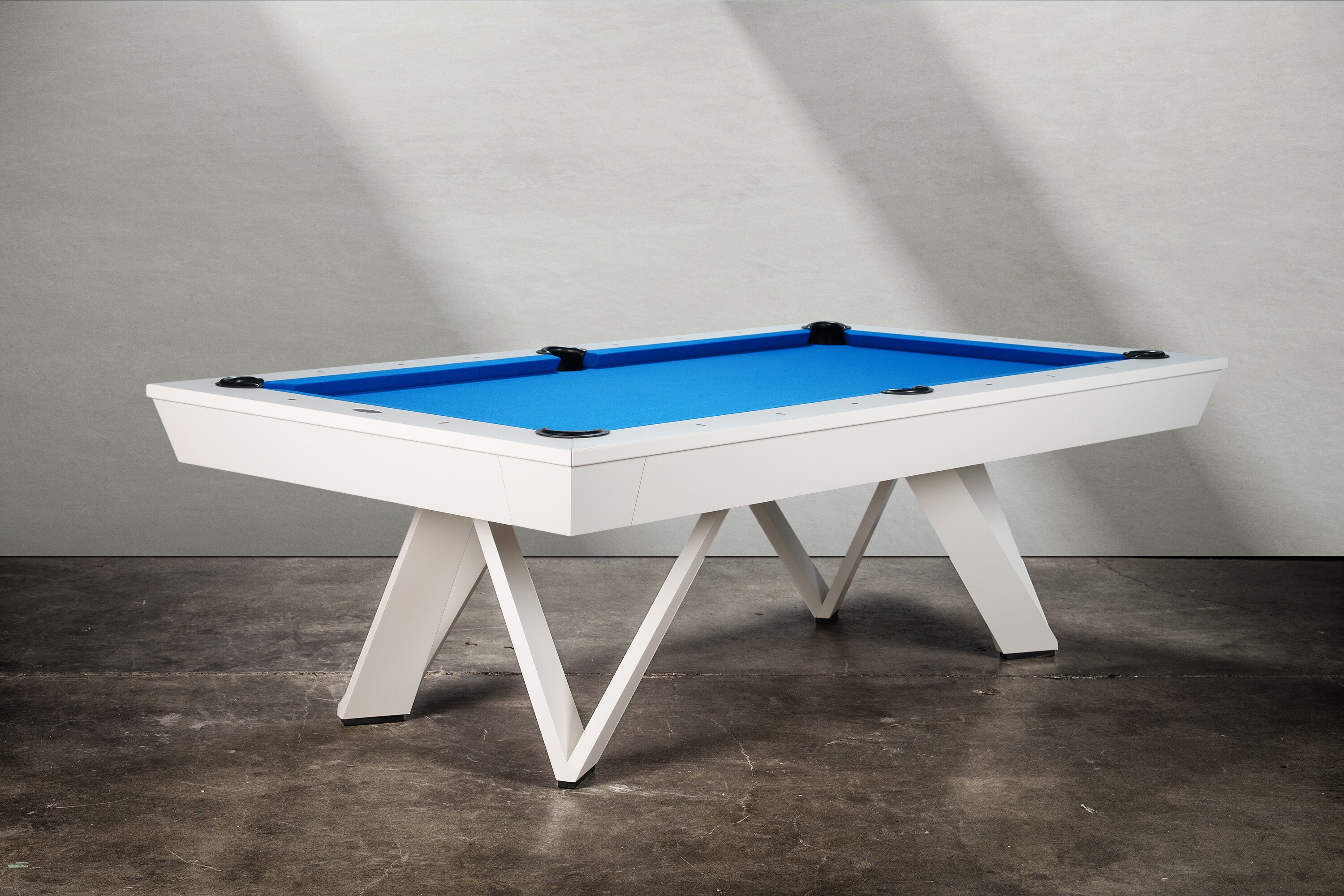 Three-quarter view of The Deco Slate Pool Table photographed in a professional studio. The crisp white finish and Euro-blue felt create a bold contrast, while the geometric base anchors the table with modern Art Deco character. A commanding piece that feels equally at home in luxury residences or design-forward