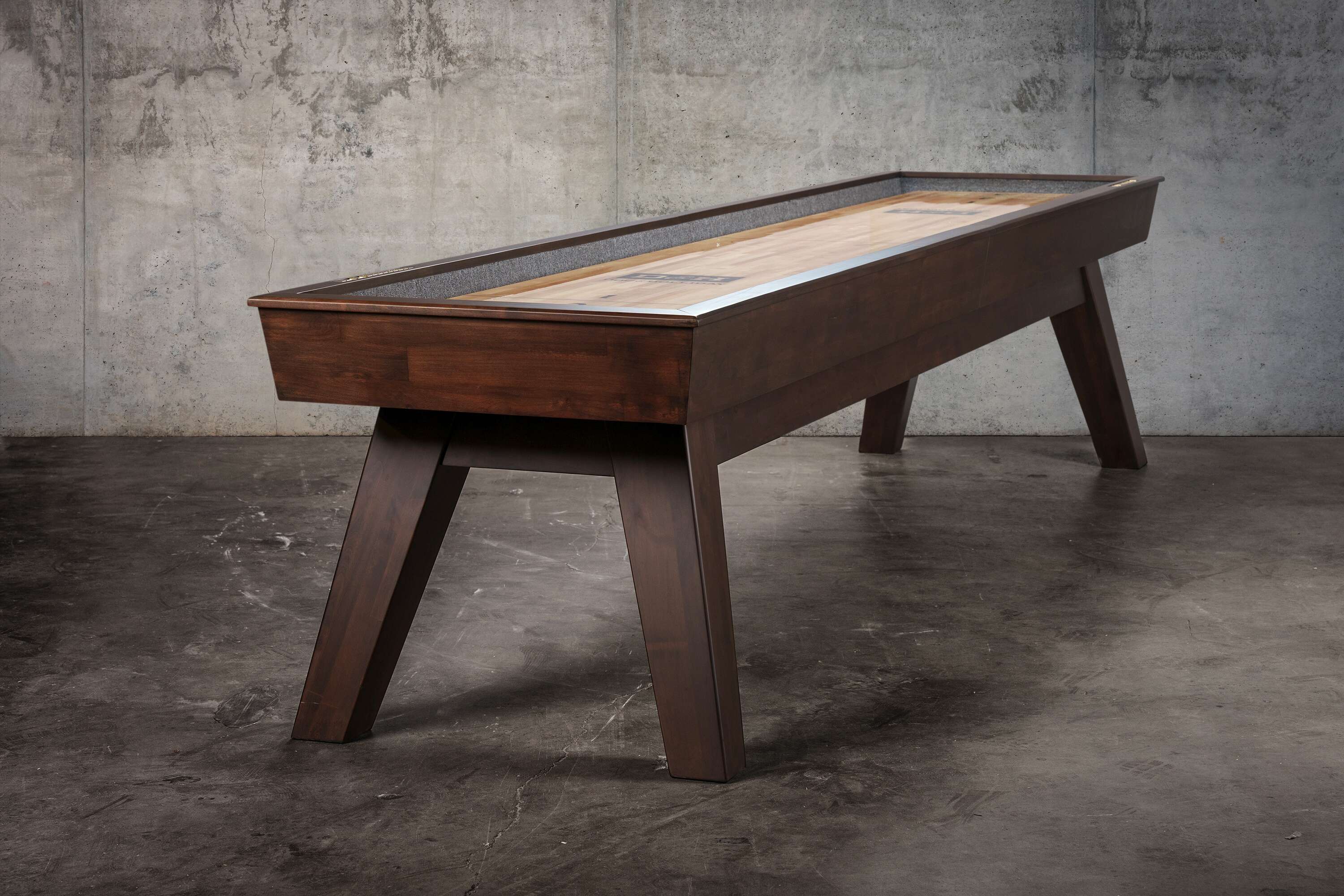 Three-quarter view of the George Shuffleboard Table in Antique Coffee finish, photographed in a professional studio, highlighting its flared mid-century legs, recessed scoring layout, and polished maple butcher block playfield designed for smooth, precise play.