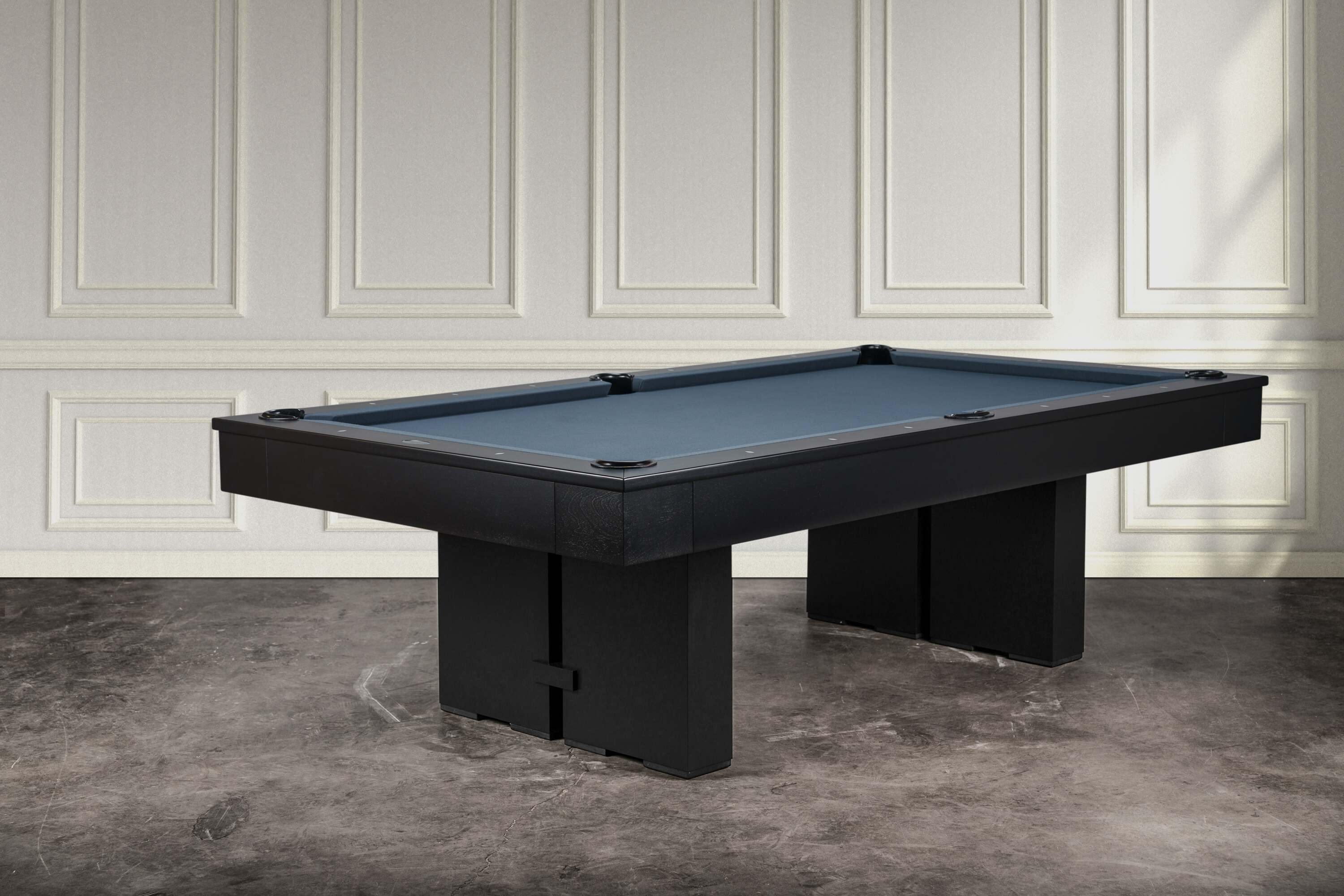 Three-quarter lifestyle view of the Jackies slate pool table by Doc & Holliday in sleek black maple finish, with block pedestal legs, tapered rails, and leather drop pockets. Proudly made in the USA, this slate billiard table is designed for modern interiors.