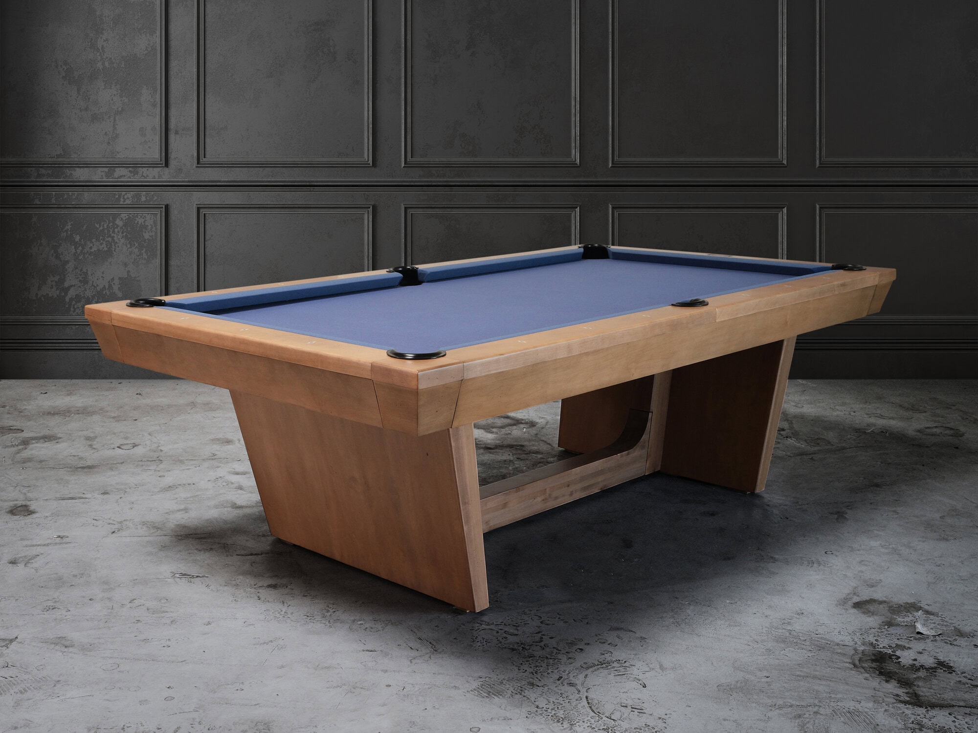 Three quarter hero view of the Doc and Holliday Kaci Slate Pool Table in glazed maple on concrete floor with luxury modern lifestyle setting