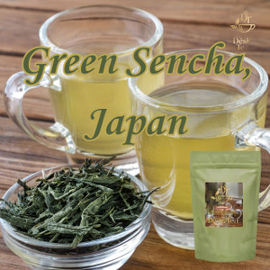 Two glass mugs filled with light green tea sit behind a small glass bowl of loose Sencha green tea leaves on a warm wooden tabletop.