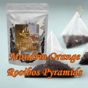 Pyramid tea sachets arranged neatly beside dried citrus peel and rooibos leaves on a warm surface