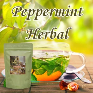 Desir Tea Peppermint Herbal tea sitting next to a glass cup filled with fresh mint leaves and warm tea.