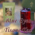 Desir Tea Blue Eyes Tisane Tea next to a tall glass of red iced tea garnished with dark petals.